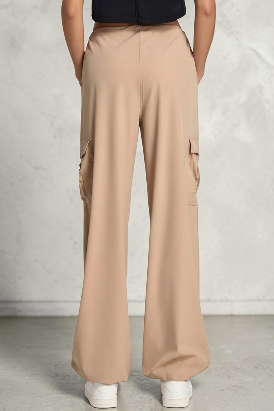 SOLID APPRL beige cargo pants with side pockets and a wide-leg fit worn by a model from the back view.