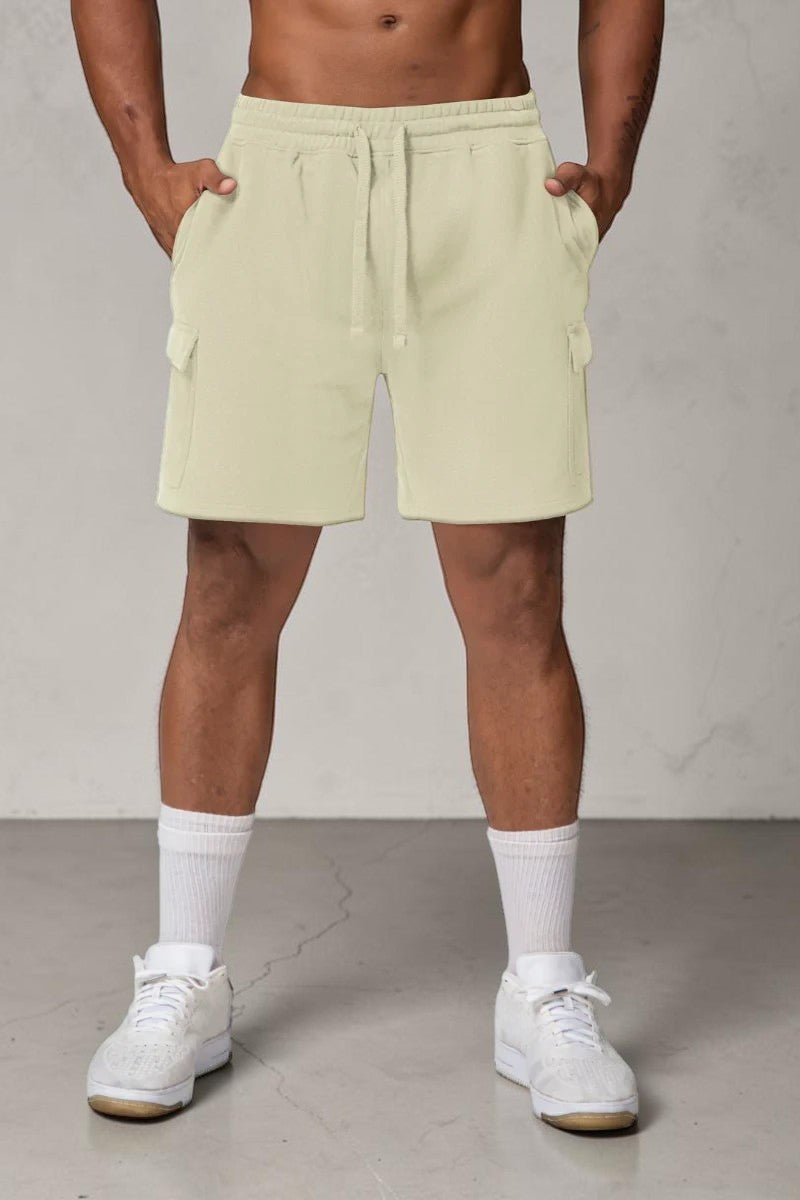 Model wearing beige SOLID APPRL fleece cargo shorts with side pockets, drawstring waist, and relaxed athletic fit.
