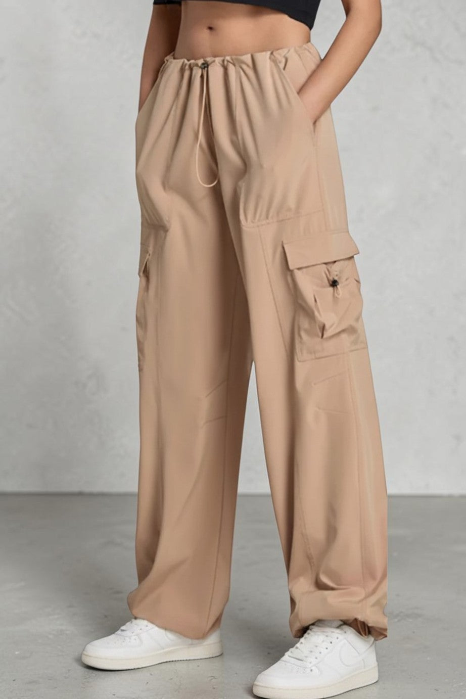 SOLID APPRL beige wide-leg cargo pants with side pockets, drawstring waist, and relaxed fit worn with sneakers.