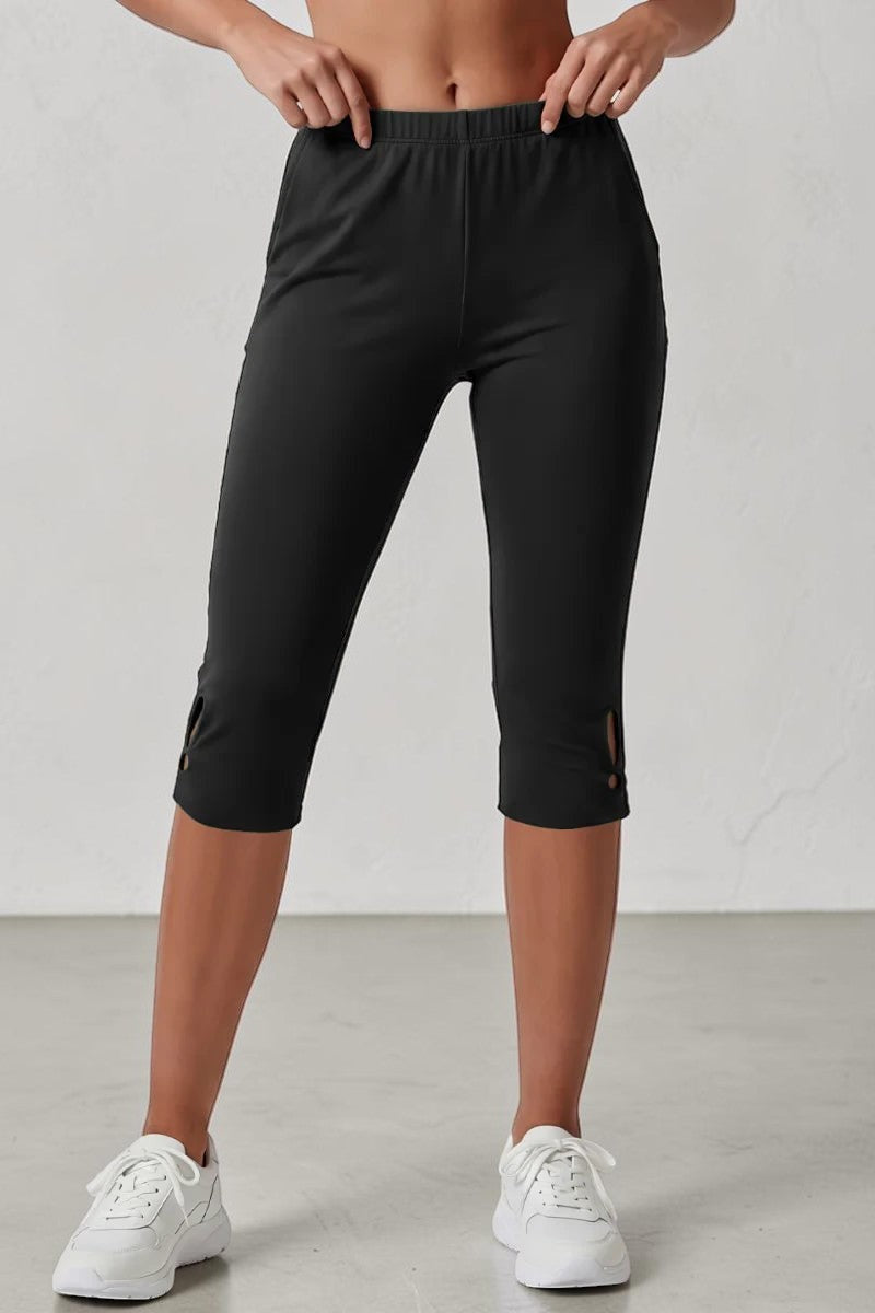 Model wearing black SOLID APPRL high-rise athletic capri leggings with side pockets and hem cutout detail.