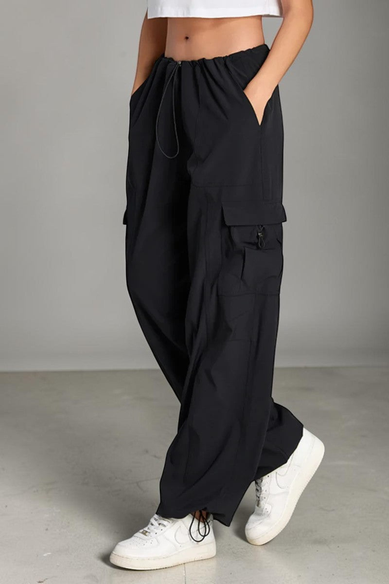 SOLID APPRL black cargo pants with a drawstring waist and side pockets worn by a model with white sneakers