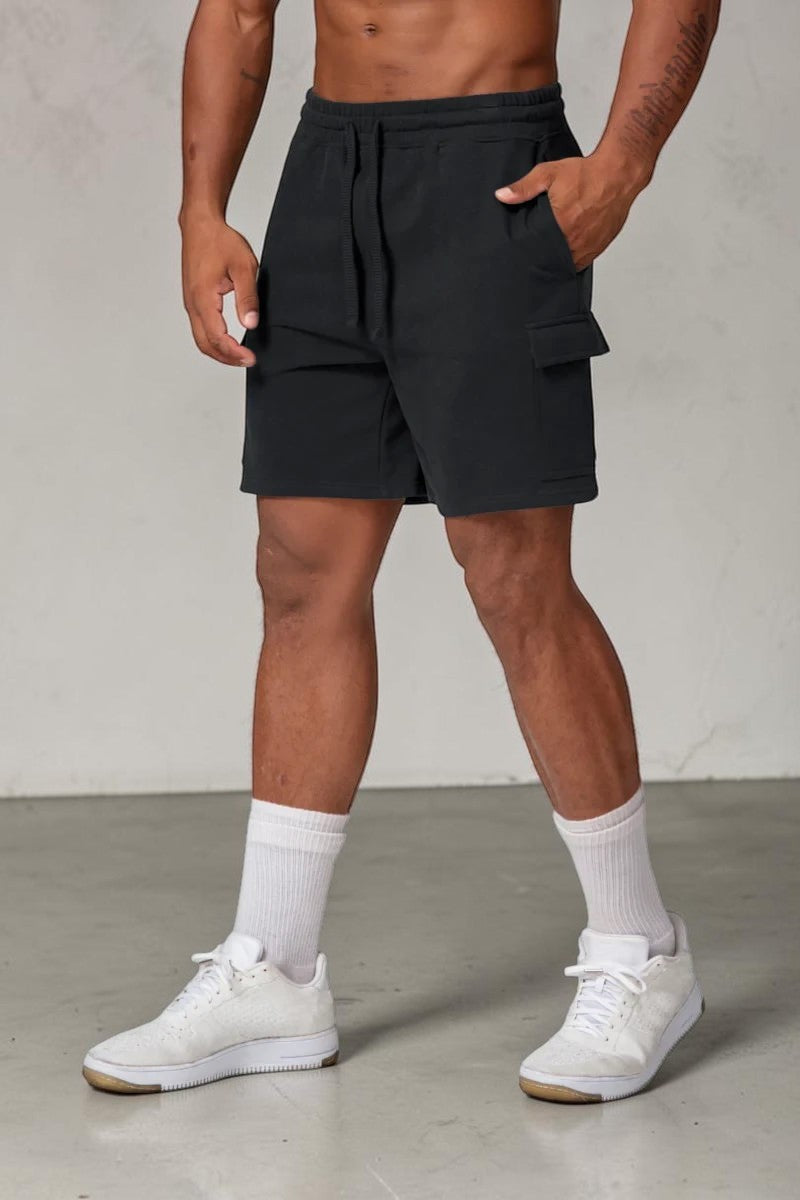 SOLID APPRL black fleece cargo shorts with drawstring waist and side pockets worn by a model in white sneakers.