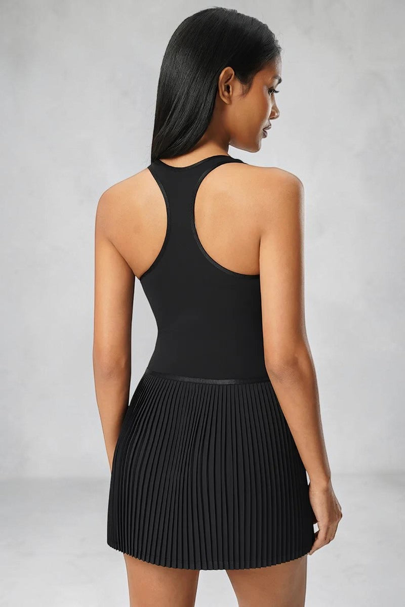 Model wearing a black SOLID APPRL racerback tennis dress with a pleated skirt, back view.