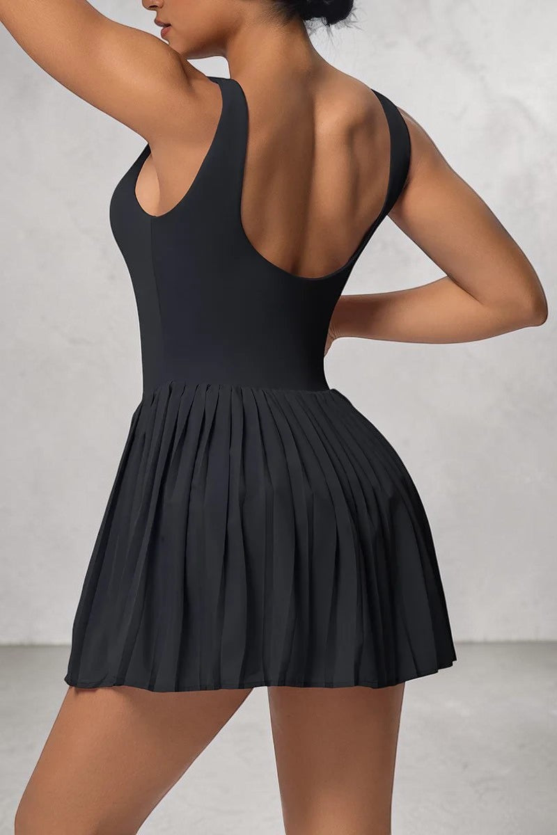 Model wearing a black SOLID APPRL pleated athletic tennis dress with a scoop back and moisture-wicking fabric.