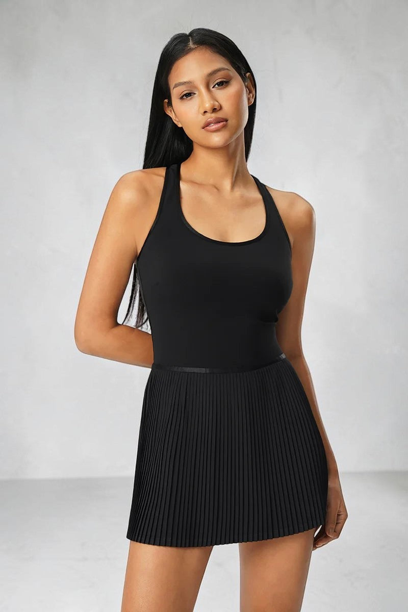 Model wearing a black SOLID APPRL moisture-wicking athletic tennis dress with a racerback and pleated skirt.