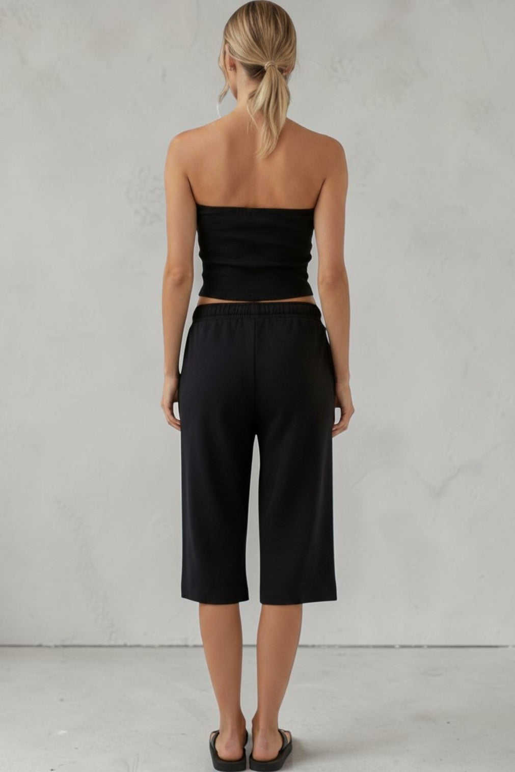 Model wearing a SOLID APPRL black two-piece set with a strapless tube top and cropped wide-leg sweat jorts.