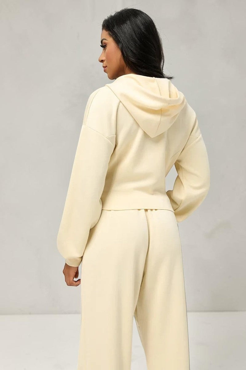 Model wearing a cream SOLID APPRL velour cropped zip-up hoodie and matching wide-leg lounge pants from behind.