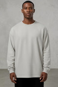 Model wearing a light grey SOLID APPRL long sleeve crewneck shirt with a relaxed fit and ribbed cuffs.