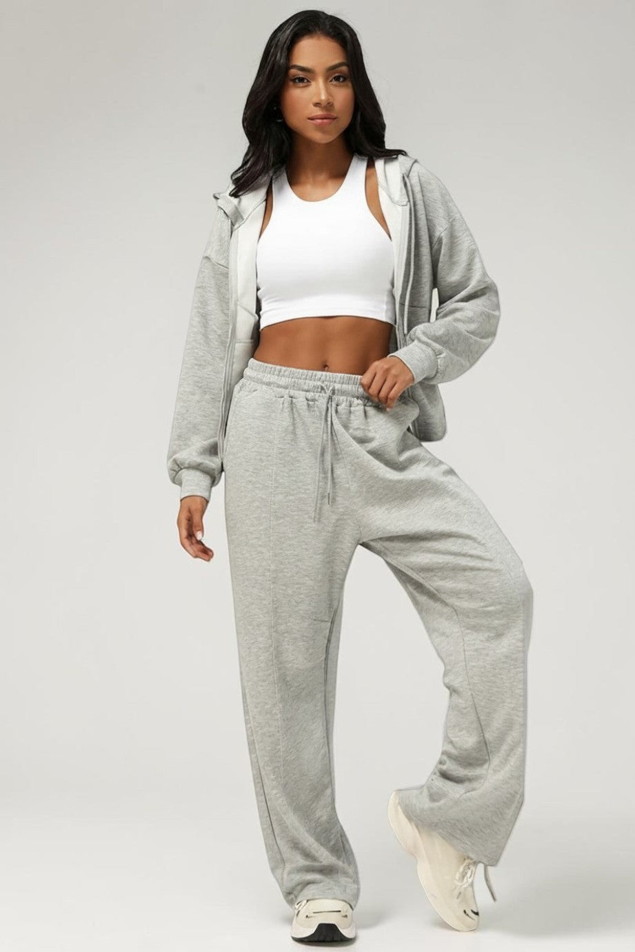 Model wearing a SOLID APPRL grey zip-up hoodie and matching wide-leg sweatpants with a white crop top