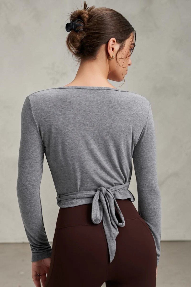 SOLID APPRL grey long sleeve wrap top with tie-front detail, worn with brown leggings for a casual athleisure look.