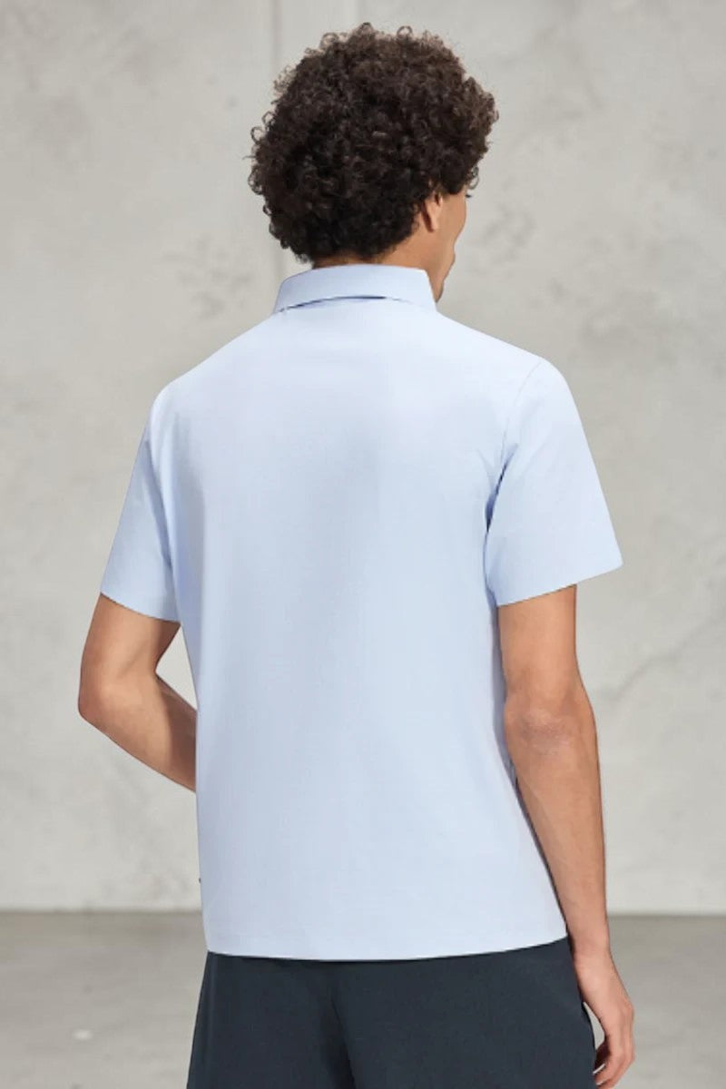SOLID APPRL light blue short sleeve polo shirt on a man with curly hair, showing a tailored fit and structured collar.