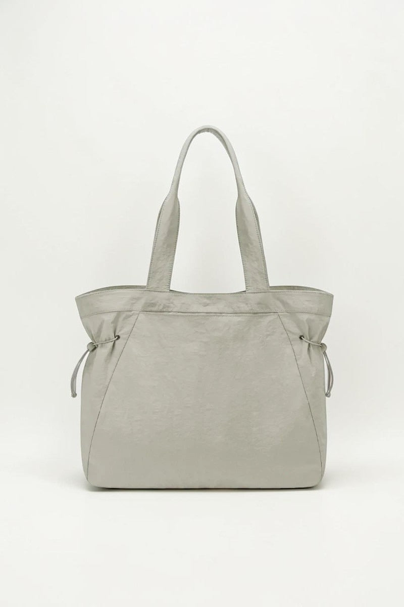 SOLID APPRL lightweight sage green tote bag with adjustable side cinches and reinforced shoulder straps.