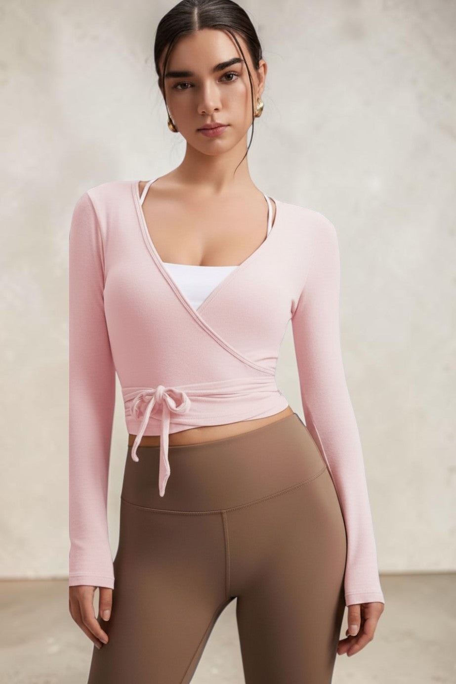 Model wearing a light pink SOLID APPRL long-sleeve wrap top with a tie-front waist and V-neckline over a white camisole.
