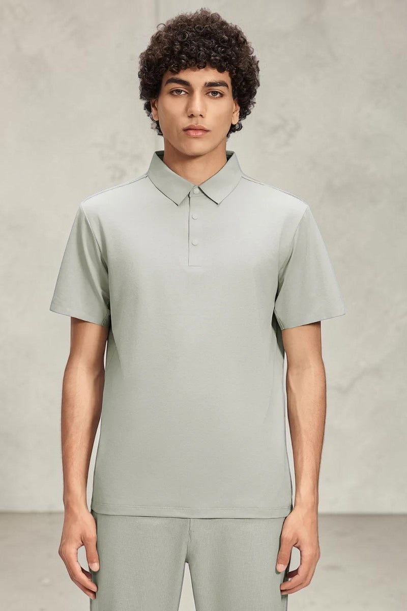 Model wearing a sage green SOLID APPRL short sleeve polo shirt with a structured collar and button placket.