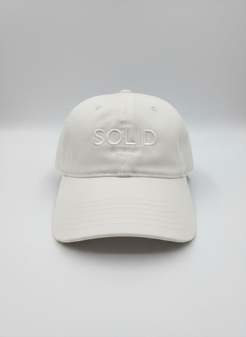 SOLID APPRL white cotton twill dad hat with embroidered logo on a plain background